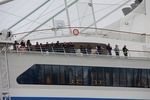 Passagiere auf einem der oberen Decks schauen auf die Menschen am Ufer
